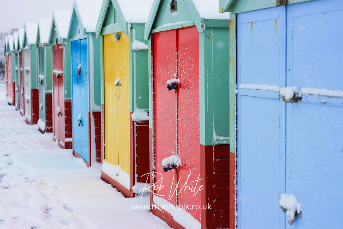 Colourful brighton beach huts reflected in the snow